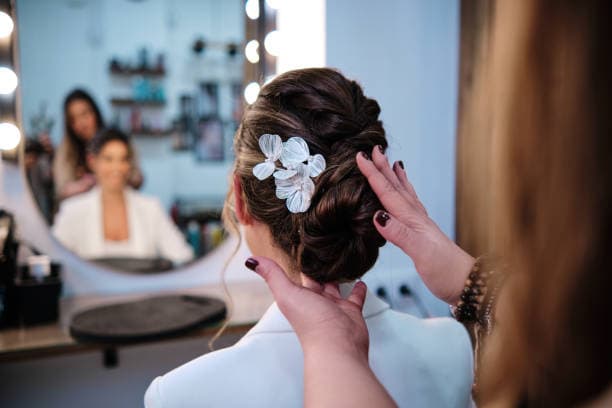 Hair stylist arranging a formal updo during a hair dressing lesson